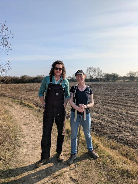 two people looking straight at the camera on the side of a field