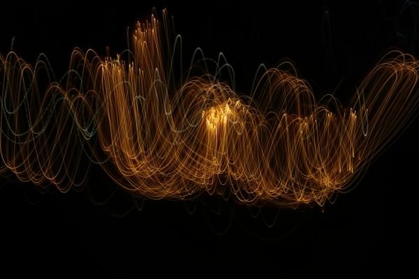 An abstract light painting of soundwaves in black and gold